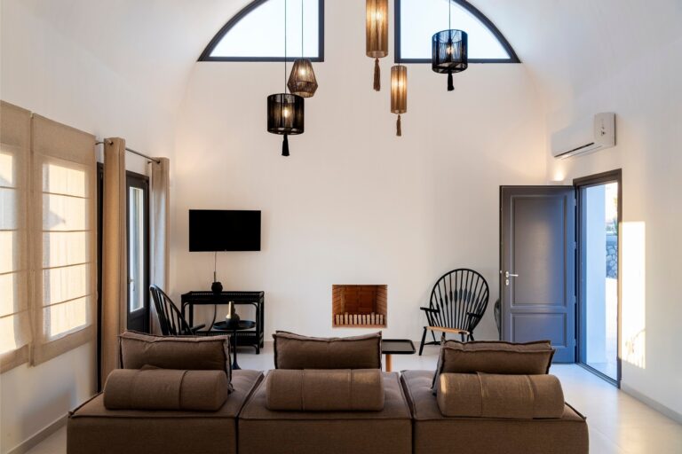 A suite living room beneath a groined vault, an arched window and a cluster of glass pendants, La Maltese Estate
