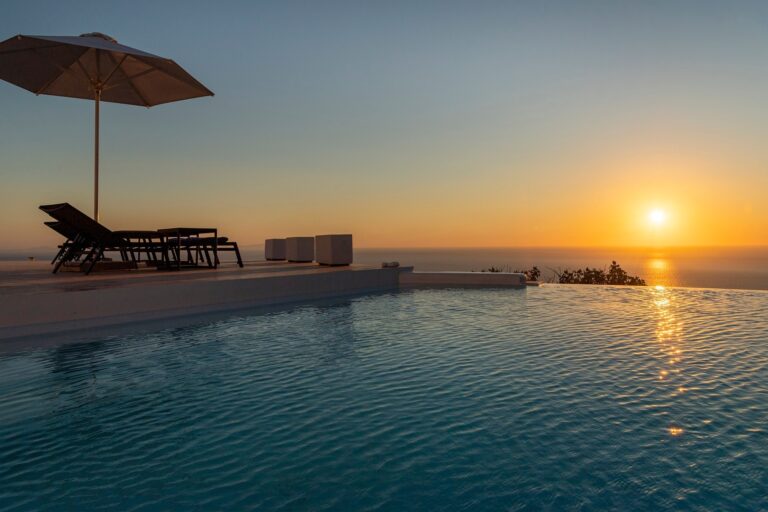 The infinity pool at sunset, a single parasol, the sun going down over the Santorini caldera, La Maltese Estate