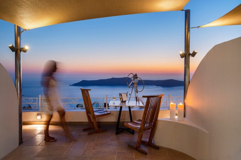 A candlelit dinner for two on a private terrace at dusk, the caldera and the Aegean falling away below, La Maltese Estate