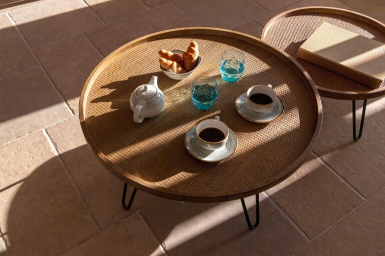 Breakfast on a round rattan table in the morning sun, coffee, croissants and cobalt glasses, La Maltese Estate