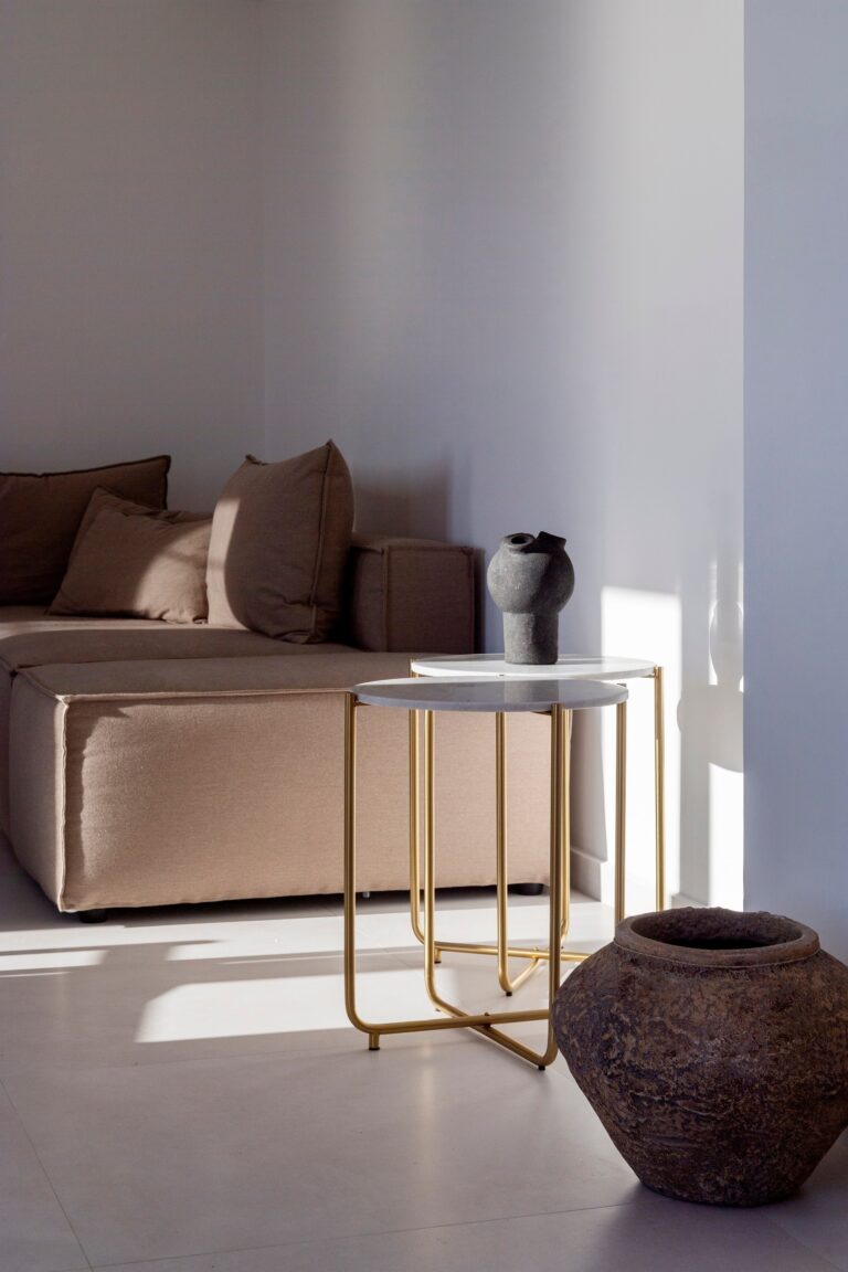 A quiet corner of a suite, a blush sofa, slim gold side tables and an antique urn in the sun, La Maltese Estate