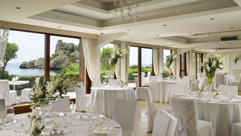 The glass-walled Scilla hall dressed for a wedding breakfast, windows open to the bay, La Plage Resort