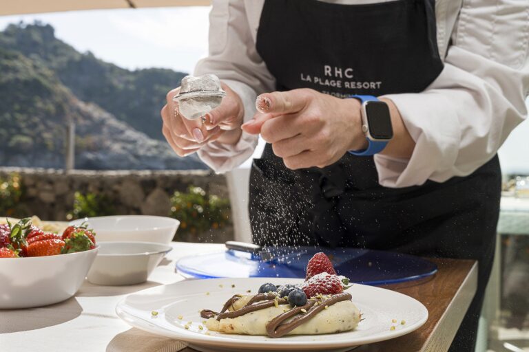 The chef finishing a dish on the terrace, the coast behind, La Plage Resort