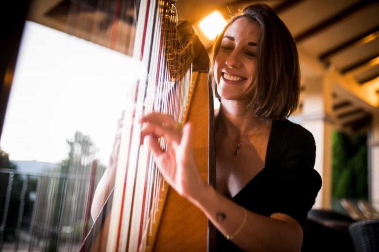 Harpist smiling as she plays on a terrace overlooking the countryside, La Semicroma