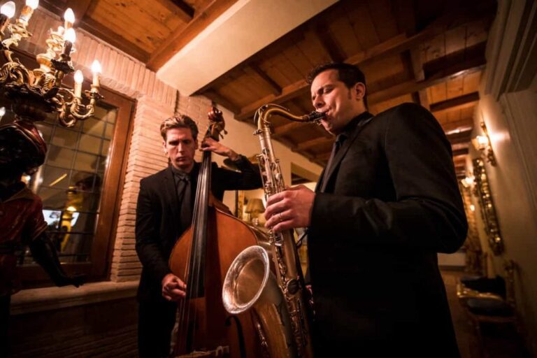 Double bass and saxophone duo playing under a timbered terrace with chandeliers, La Semicroma
