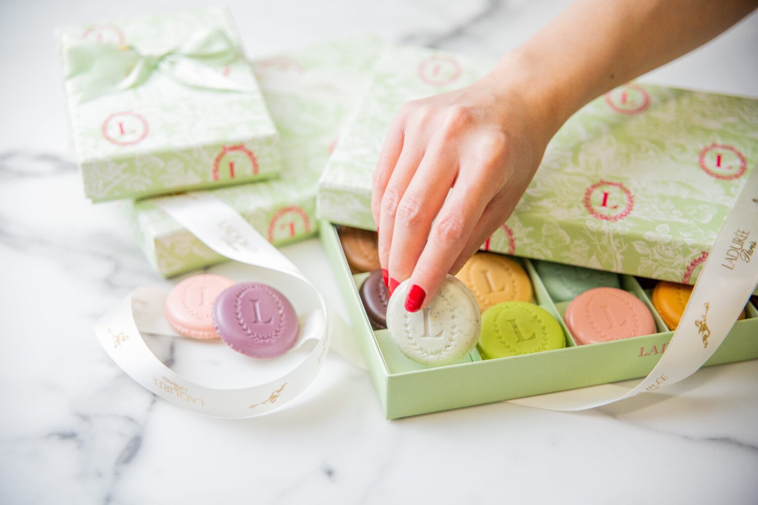A gift box of macarons and Eugénie opened on white marble with ribbon