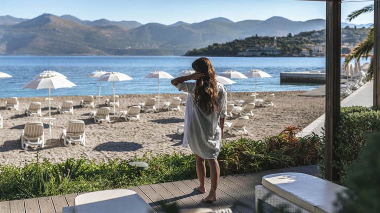 A guest on the beach terrace, looking out over rows of white parasols to the sea and the hills, Lafodia Sea Resort