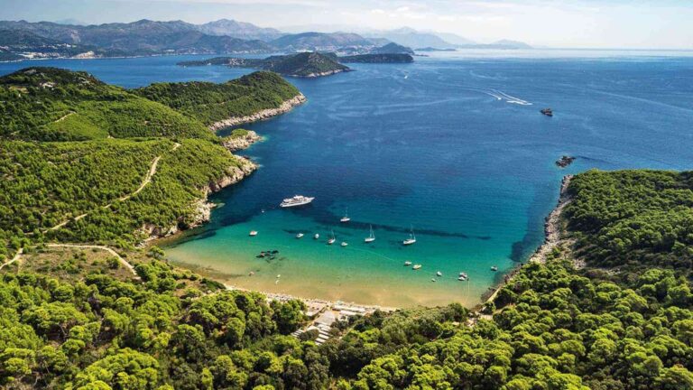 An aerial view of Lopud, a horseshoe of sandy beach and turquoise water between green headlands, Lafodia Sea Resort