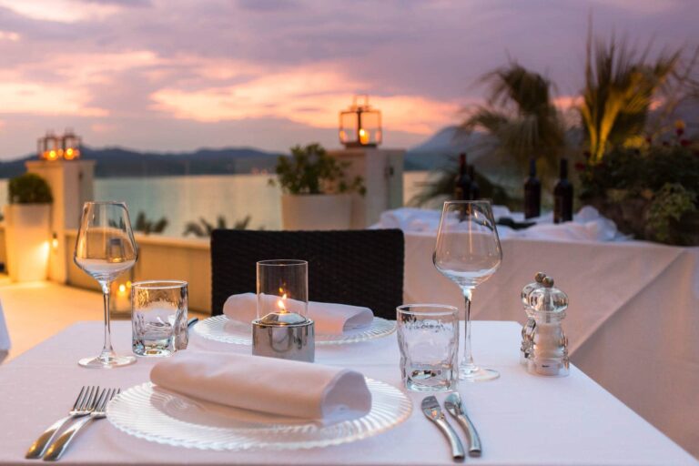A candlelit table set for dinner on a sea-view terrace, the Adriatic turning pink at sunset, Lafodia Sea Resort