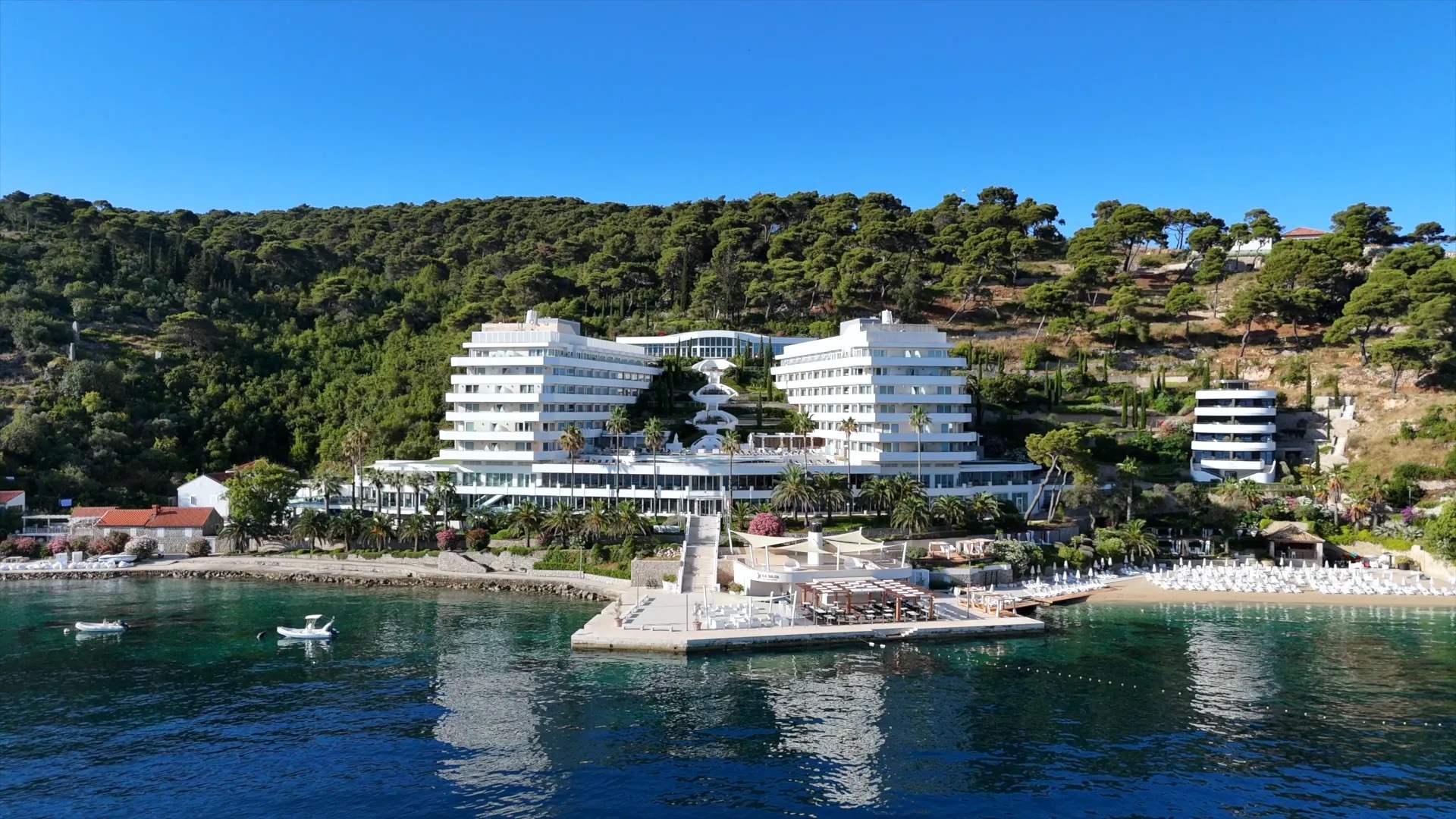The resort seen from the water, rising in white tiers above its own jetty and beach on Lopud, Lafodia Sea Resort