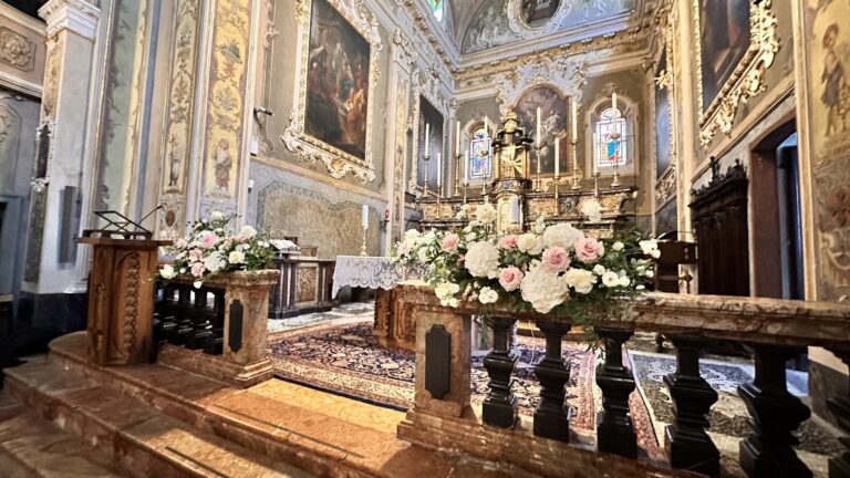 A baroque church interior with tall pedestals of pale pink and white roses before the altar rail, Lake Maggiore & Tuscany Weddings