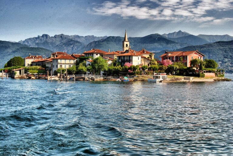 Isola dei Pescatori from the water: ochre and red houses under the campanile, the mountains behind, Borromean Islands, Lake Maggiore & Tuscany Weddings