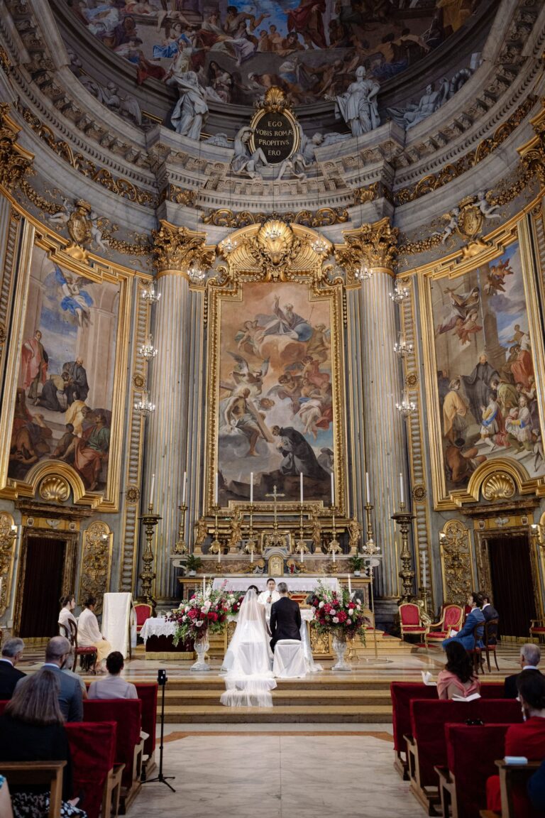 A ceremony at the high altar of a Baroque church, guests in red velvet chairs, Le Rêve