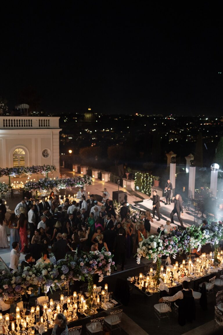 The same terrace after dark, long tables lit by candles as guests take their seats, Rome, Le Rêve