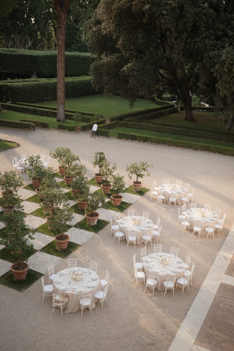 Round tables set among potted trees on a chequerboard of gravel and lawn, seen from above, Le Rêve