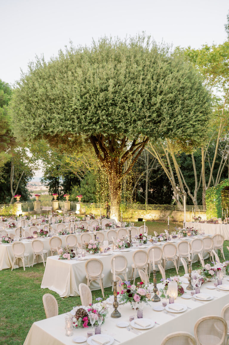 Long tables on the lawn at Villa Aurelia, Rome, under a broad tree strung with lights, Le Rêve
