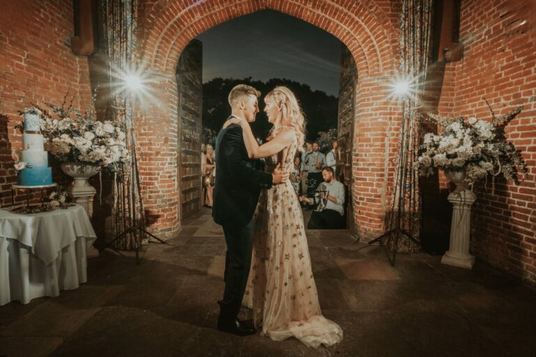 A first dance beneath the brick carriageway arch at night, the wedding cake and blossom on either side, Leez Priory