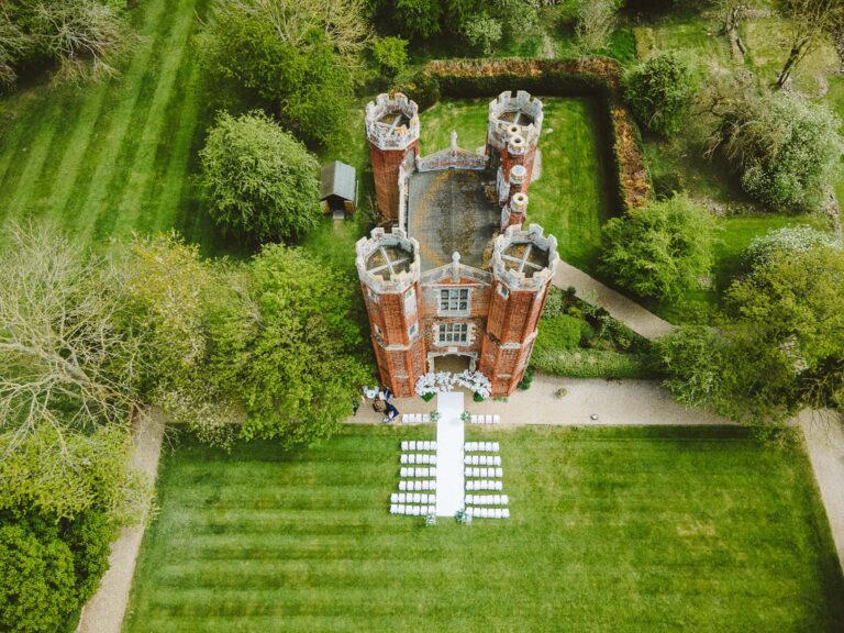 An aerial view of the Great Tower and its four turrets, an outdoor ceremony laid out on the lawn below, Leez Priory