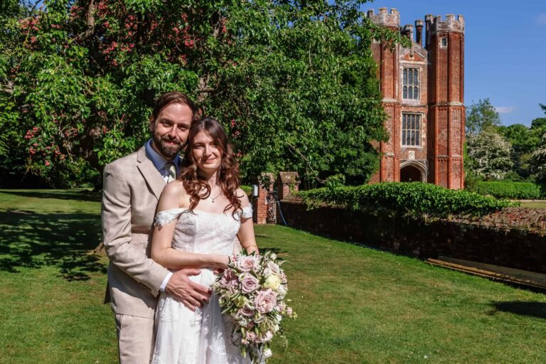 A summer portrait of the couple in the gardens with the Great Tower rising behind, Leez Priory