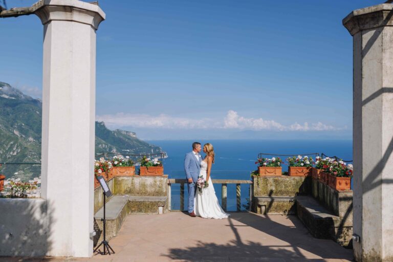 A ceremony on a Ravello terrace between two stone columns, the open sea beyond, Leo Eventi