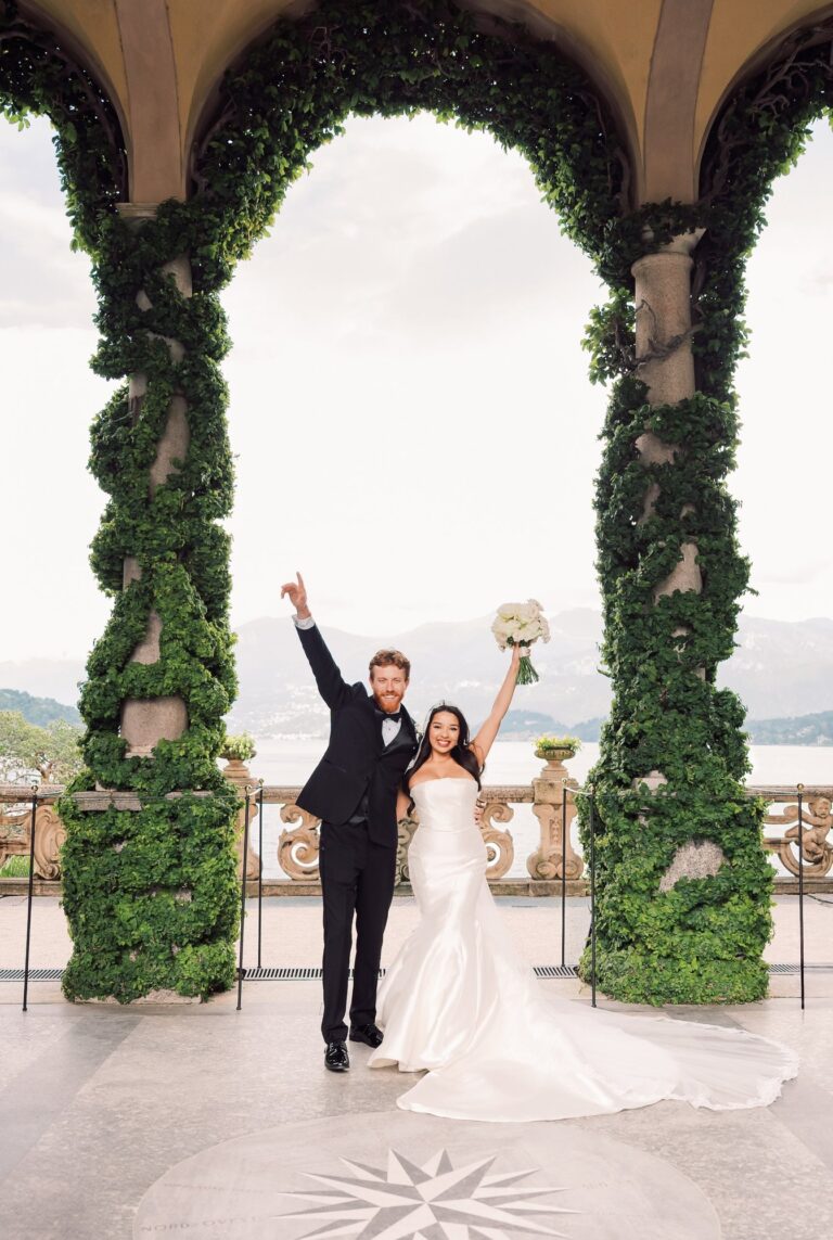 Under a tall green arch on the terrace, the lake and the mountains behind, Leo Eventi