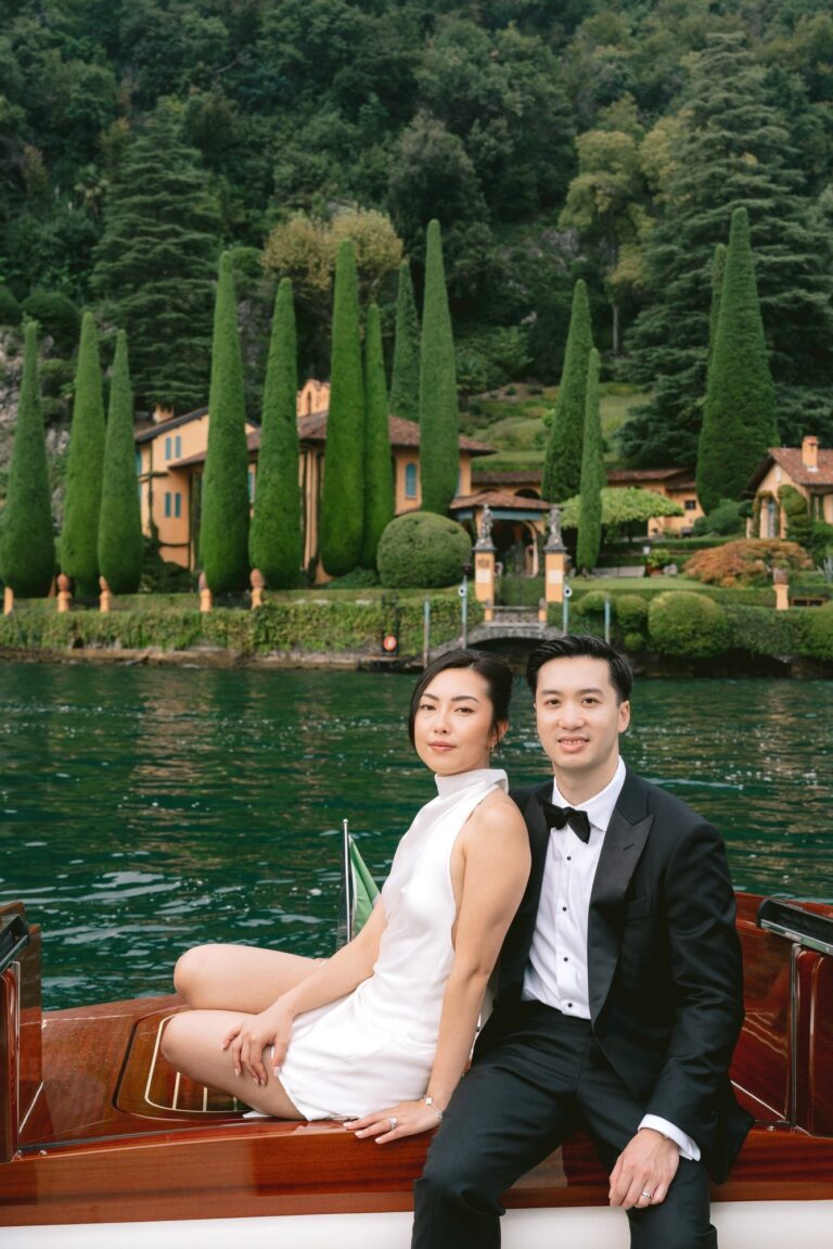 In a mahogany launch, a villa and its cypresses on the shore behind them, Leo Eventi