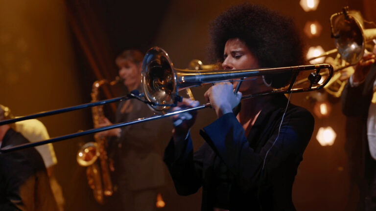 A trombone and brass players in warm stage light, Les Cigales