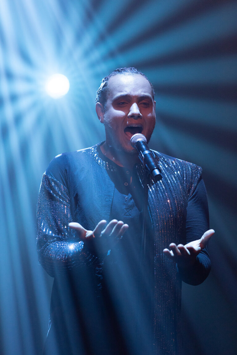 A singer with open hands in a blue beam of light, Les Cigales