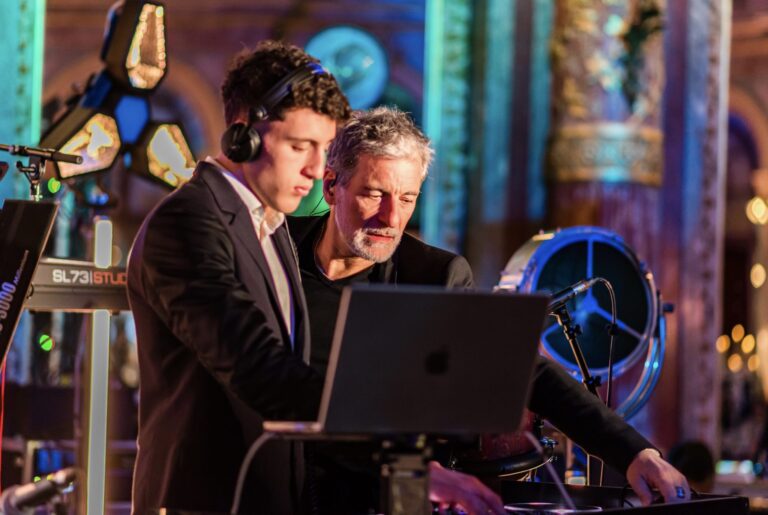 Two musicians at a laptop in an ornate venue interior, Les Cigales