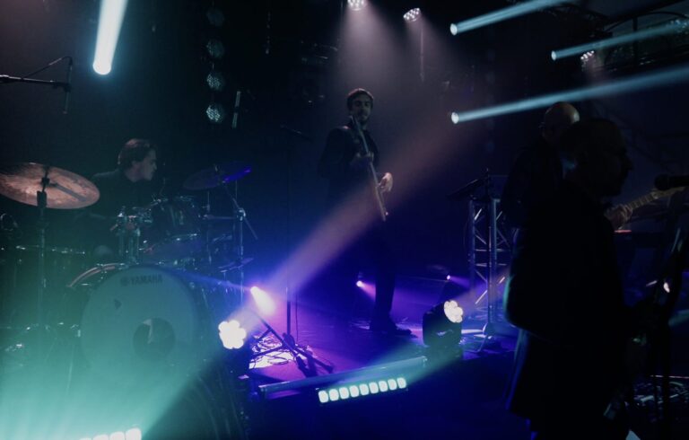 A stage with drum kit and purple and teal lighting beams, Les Cigales