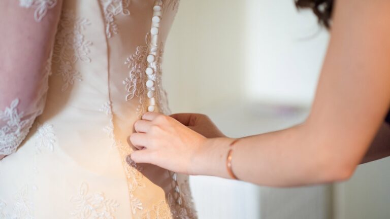Fastening the buttons on the back of a wedding dress, Lesley Cutler Bridal Wear