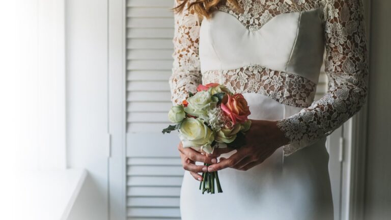 Lace-bodice wedding dress with a posy of roses held at the waist, Lesley Cutler Bridal Wear