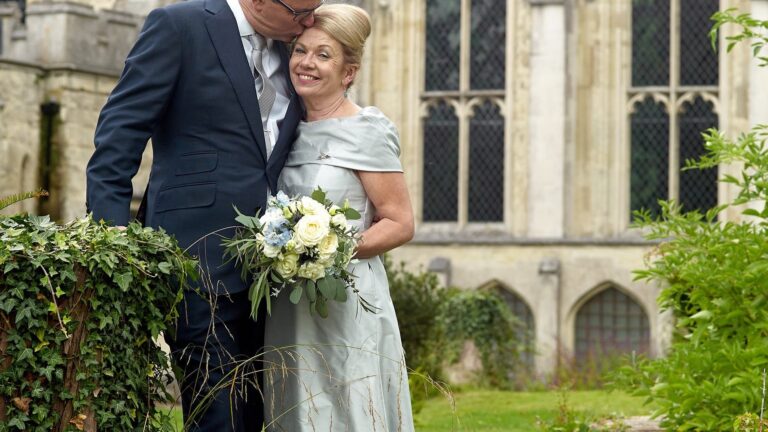 Bride in a pale green-grey gown holding a bouquet of white flowers, Lesley Cutler Bridal Wear