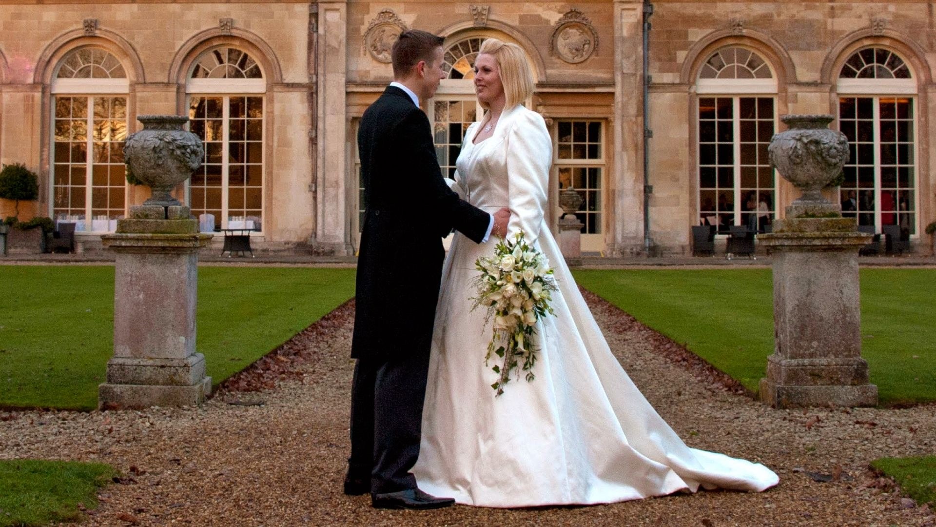Bride and groom in a formal garden in front of a stately home, Lesley Cutler Bridal Wear