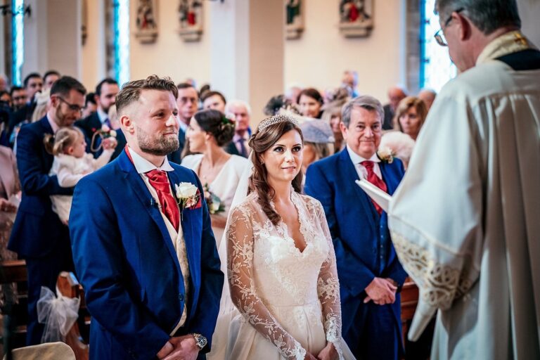 Bride and groom at the front of a church during the ceremony, Lesley Cutler Bridal Wear