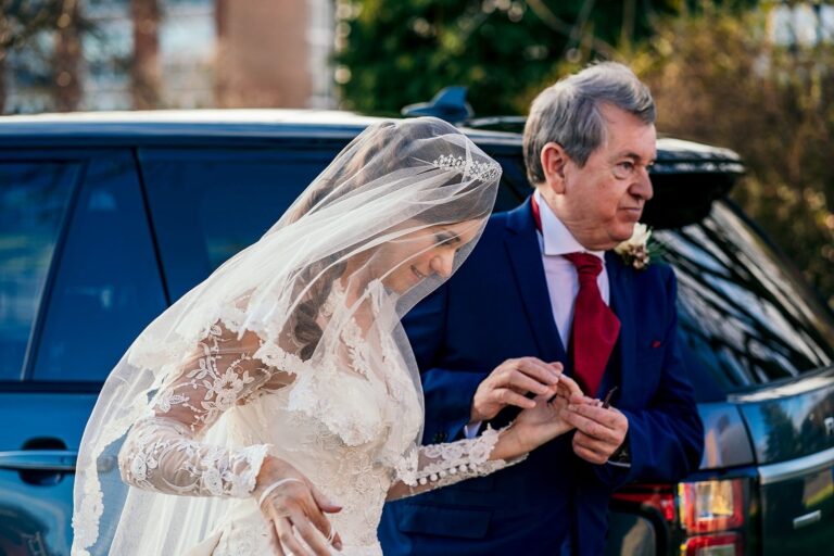 Bride in a lace veil with her father beside the wedding car, Lesley Cutler Bridal Wear