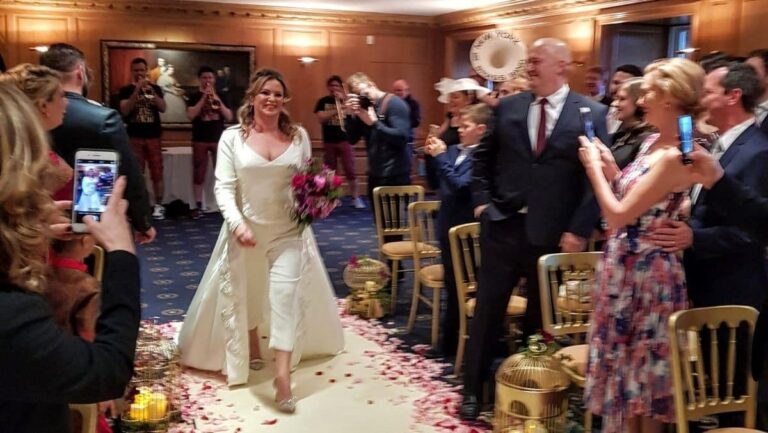 Bride walking down an aisle strewn with rose petals, Lesley Cutler Bridal Wear