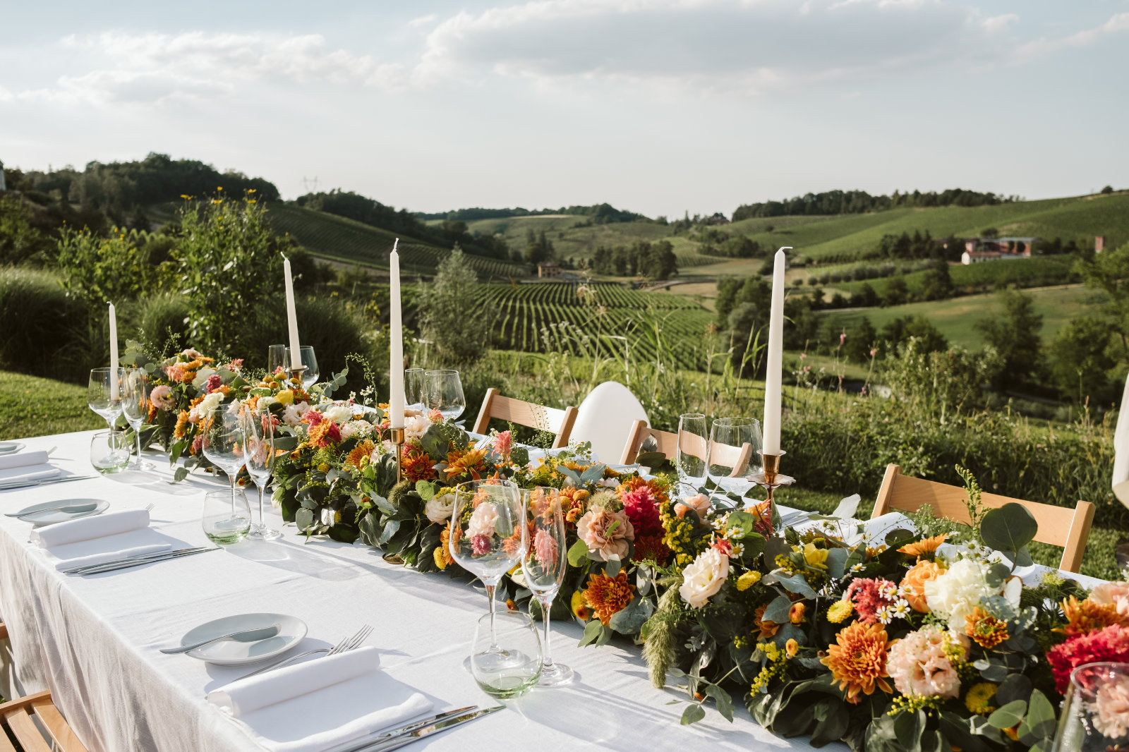 Long reception table dressed with autumn flowers on a terrace above the vineyards of the Gavi hills, Letizia T. Events
