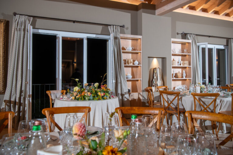 Round tables with low flowers in a stone-and-timber reception room, Letizia T. Events