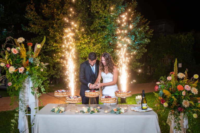 Cake table with sparkle fountains and tall flower arrangements at night, Letizia T. Events