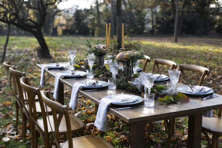 Banquet table with candles and greenery set under autumn trees, Letizia T. Events