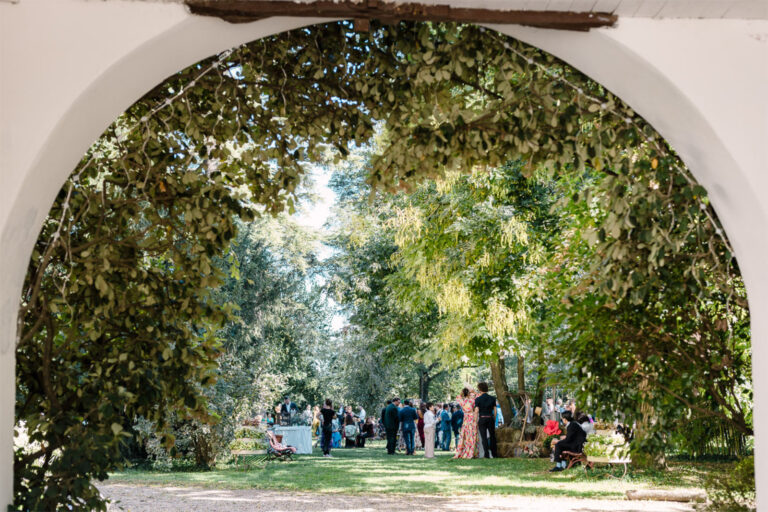 Guests walking under a garden archway towards the wedding reception, Letizia T. Events