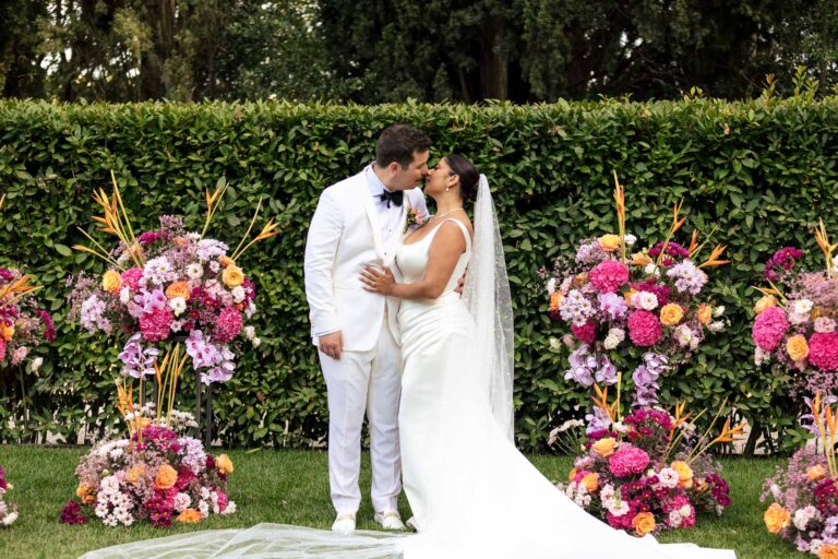 Matt and Zayna kiss between the flower arrangements after their ceremony at Villa Valentini Bonaparte, Light & Dreams