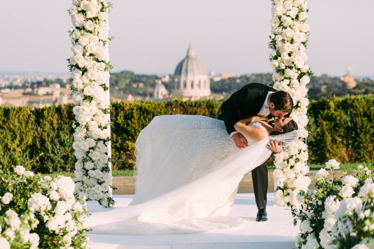 John dips Cristina under the flower arch at Villa Miani, Rome, with the dome of St Peter's behind, Light & Dreams