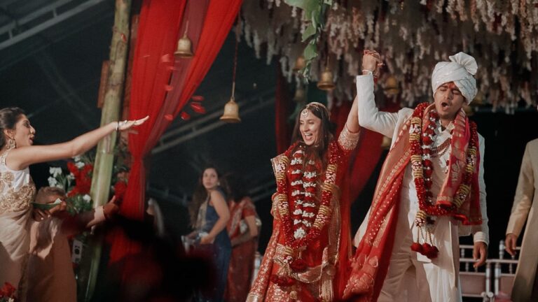 Devina and Yash raise their hands as their ceremony ends under red drapes (film still), Lights and Magic