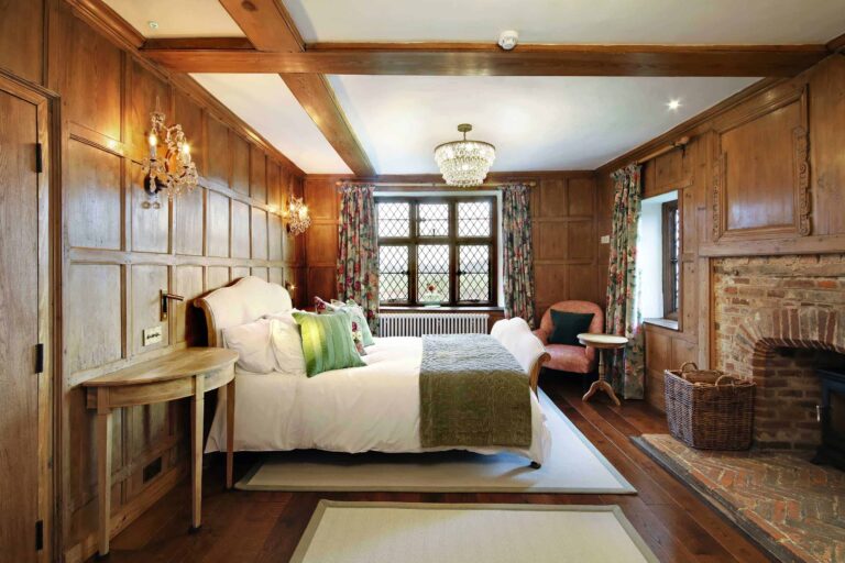 A wood-panelled bedroom in the Manor House with leaded windows and a brick fireplace, Lillibrooke Manor
