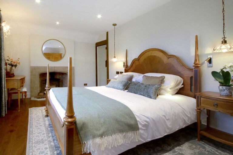 A Manor House bedroom with a carved wooden bed and an open fireplace, Lillibrooke Manor