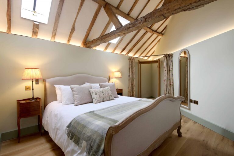 The Old Piggery double suite, with a vaulted beamed ceiling and table lamps either side of the bed, Lillibrooke Manor