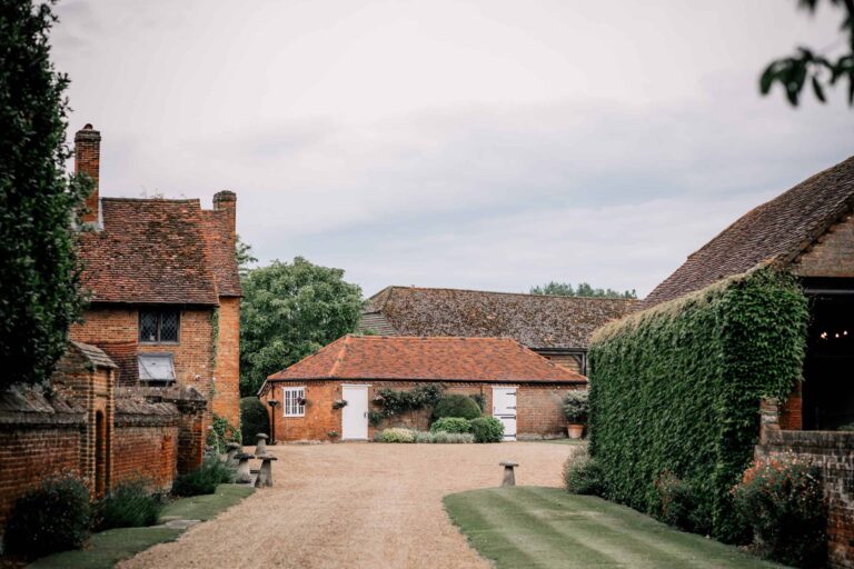 The gravel drive between the red-brick Manor House, a low brick outbuilding and an ivy-covered barn wall, Lillibrooke Manor