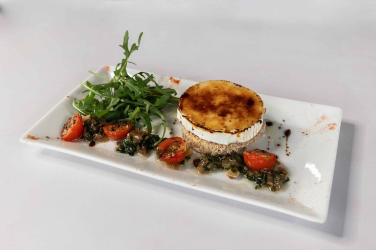 A plated starter of grilled goat's cheese with tomatoes and rocket, Lillibrooke Manor